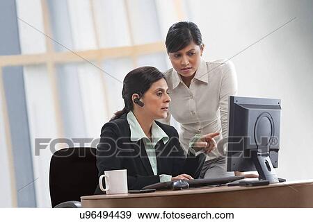 Female executives discussing while looking at computer View Large Photo Image Stock Photo - Female executives discussing while looking at computer . Fotosearch