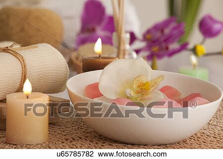 Stock Image - Flowers in a bowl with candles and bath scrub . Fotosearch