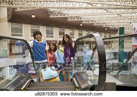 Friends holding shopping bags on escalator View Large Photo Image Stock Image - Friends holding shopping bags on escalator . Fotosearch