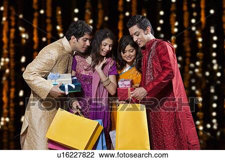 Stock Image - Friends peeping into a shopping bag. Fotosearch