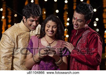 Friends reading an sms on a mobile phone View Large Photo Image Stock Photograph - Friends reading an sms on a mobile phone. Fotosearch