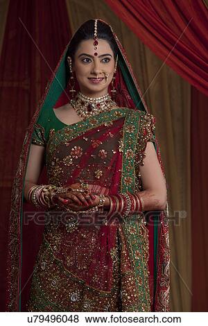 Front view of beautiful young Indian bride standing while looking away View Large Photo Image Stock Photo - Front view of beautiful young Indian bride standing while looking away . Fotosearch