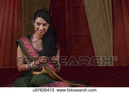 Stock Image - Front view of smiling young bride sitting . Fotosearch