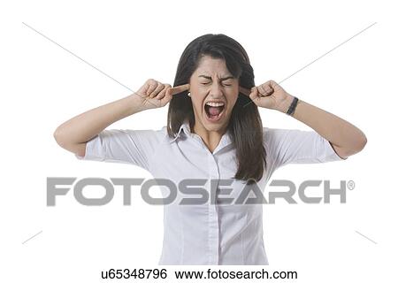 Stock Photograph - Frustrated businesswoman with fingers in ears shouting over white background. Fotosearch