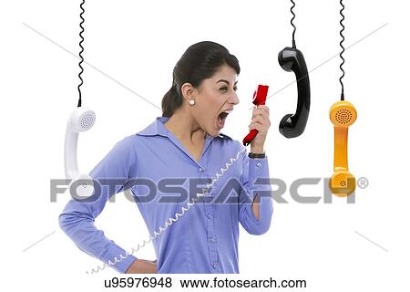 Frustrated businesswoman yelling into telephone receiver against white background View Large Photo Image Stock Photo - Frustrated businesswoman yelling into telephone receiver against white background. Fotosearch