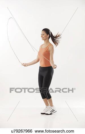 Full length of a young woman exercising with a jump rope over white background View Large Photo Image Stock Photograph - Full length of a young woman exercising with a jump rope over white background . Fotosearch