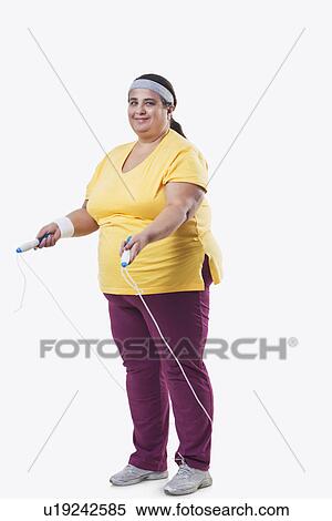 Stock Photography - Full length of an overweight female with skipping rope over white background . Fotosearch
