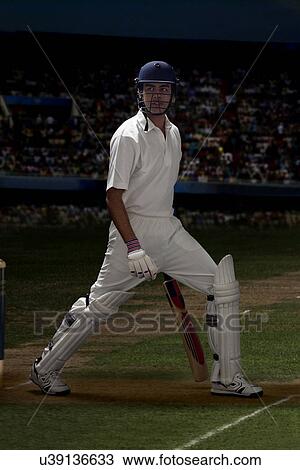 Stock Image - Full length of batsman stretching on cricket field . Fotosearch