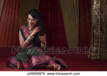 Stock Image - Full length of beautiful young bride smiling while looking down . Fotosearch