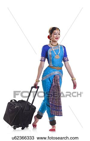 Stock Image - Full length of Bharatanatyam dancer with luggage against white background. Fotosearch
