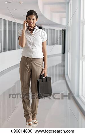 Full length of businesswoman on phone call at office View Large Photo Image Stock Image - Full length of businesswoman on phone call at office . Fotosearch
