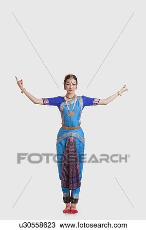 Stock Image - Full length of dancer in traditional wear performing Bharatanatyam against white background. Fotosearch