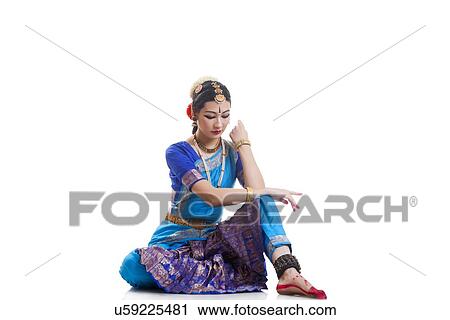 Stock Image - Full length of dancer in traditional wear performing Bharatanatyam against white background. Fotosearch