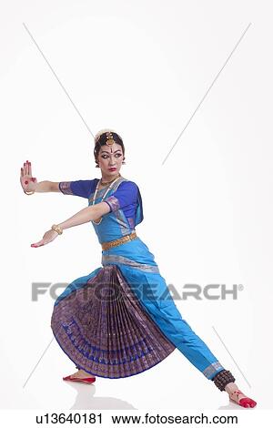 Stock Image - Full length of Indian female performing classical dance over white background. Fotosearch