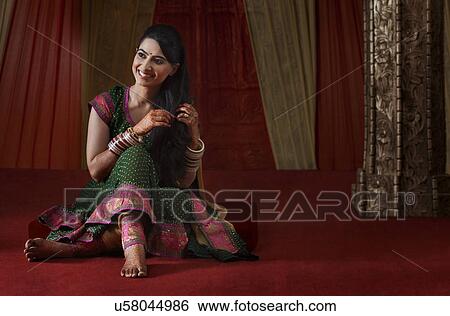 Full length of smiling Indian bride sitting while looking away View Large Photo Image Stock Photograph - Full length of smiling Indian bride sitting while looking away . Fotosearch
