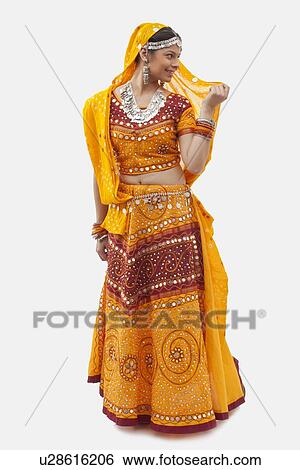 Stock Photograph - Full length of woman in chaniya choli looking away against white background. Fotosearch