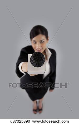 Full length of woman reporter holding out microphone against colored background View Large Photo Image Stock Image - Full length of woman reporter holding out microphone against colored background . Fotosearch