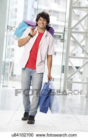 Full length of young man carrying shopping bags View Large Photo Image Stock Image - Full length of young man carrying shopping bags . Fotosearch