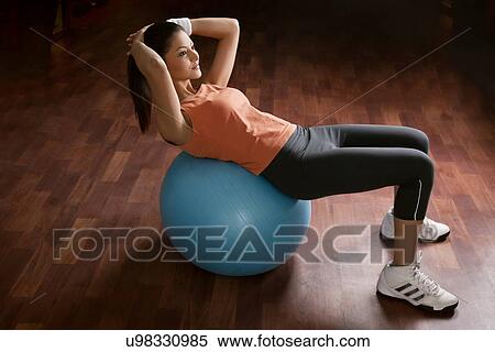 Full length of young woman doing abdominal exercise on a fitness ball View Large Photo Image Stock Photography - Full length of young woman doing abdominal exercise on a fitness ball . Fotosearch