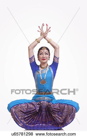 Stock Photo - Full length of young woman performing Indian Bharat Natyam dance over white background. Fotosearch