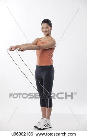Stock Photograph - Full length portrait of a young woman with jump rope over white background . Fotosearch