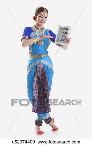 Stock Photo - Full length portrait of Bharatanatyam dancer showing web page on digital tablet on while background. Fotosearch