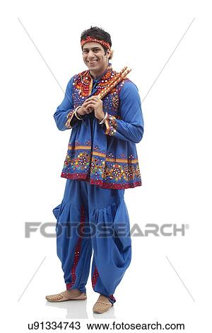 Full length portrait of happy young man in kedia and dhoti holding dandiyas over white background View Large Photo Image Stock Image - Full length portrait of happy young man in kedia and dhoti holding dandiyas over white background. Fotosearch