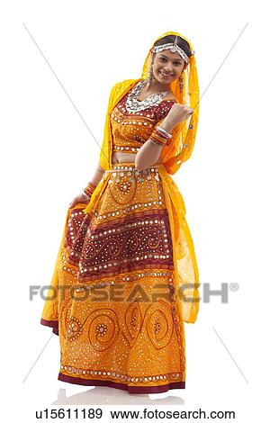 Stock Photo - Full length portrait of happy young woman wearing chaniya choli isolated over white background. Fotosearch