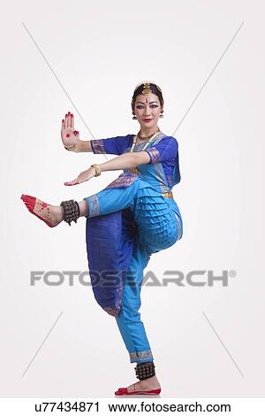 Stock Image - Full length portrait of young woman performing Bharatanatyam over white background. Fotosearch