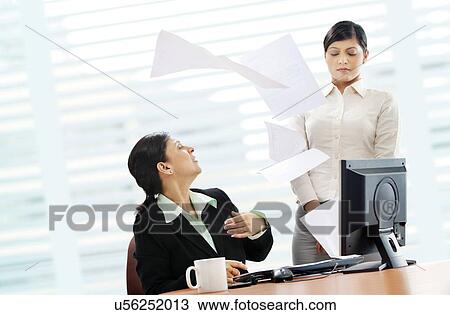 Furious mature businesswoman throwing papers on female executive View Large Photo Image Stock Image - Furious mature businesswoman throwing papers on female executive . Fotosearch