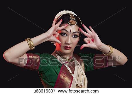 Stock Photo - Furious young woman performing Bharatanatyam on black background. Fotosearch