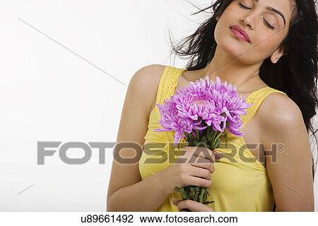 Stock Image - Girl enjoying the scent of flowers . Fotosearch