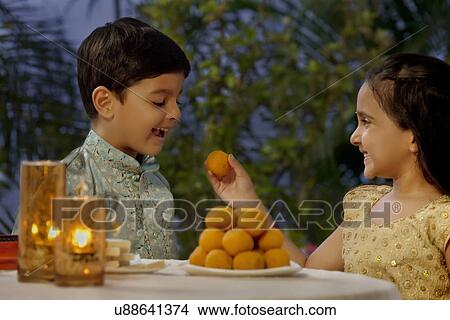 Girl feeding her brother a laddoo View Large Photo Image Picture - Girl feeding her brother a laddoo . Fotosearch