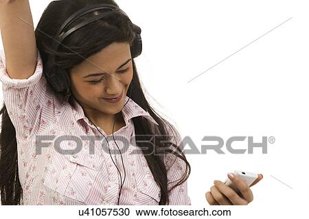 Stock Image - Girl listening to music on her mobile phone . Fotosearch