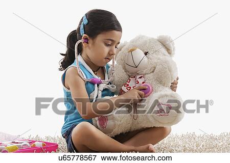 Stock Photo - Girl playing doctor with her teddy bear . Fotosearch