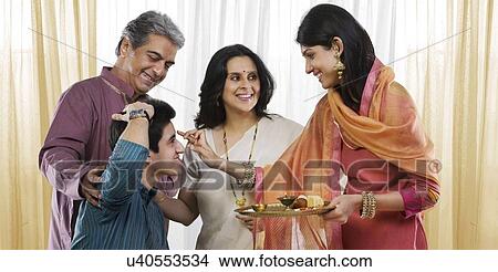 Picture - Girl putting a tikka on her brothers head . Fotosearch
