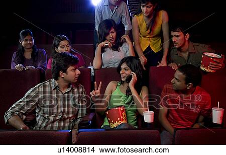 Girl talking on a mobile phone in a cinema hall View Large Photo Image Picture - Girl talking on a mobile phone in a cinema hall . Fotosearch