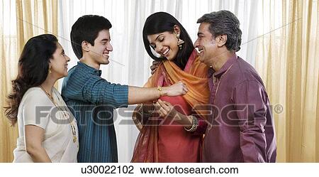 Girl tying a rakhi on her brothers hand View Large Photo Image Stock Image - Girl tying a rakhi on her brothers hand . Fotosearch