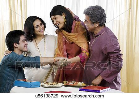 Stock Photo - Girl tying a rakhi on her brothers hand . Fotosearch
