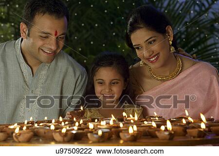 Stock Image - Girl with family arranging diyas . Fotosearch