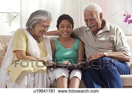 Granddaughter looking at a photo album with her grandparents View Large Photo Image Stock Image - Granddaughter looking at a photo album with her grandparents. Fotosearch