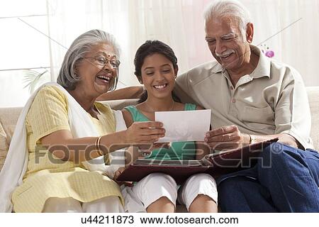 Granddaughter looking at a photo album with her grandparents View Large Photo Image Stock Image - Granddaughter looking at a photo album with her grandparents. Fotosearch
