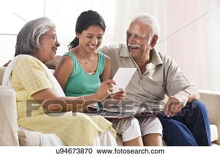 Granddaughter looking at a photo album with her grandparents View Large Photo Image Stock Image - Granddaughter looking at a photo album with her grandparents. Fotosearch