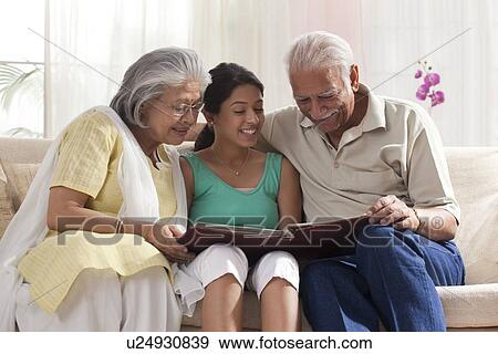 Granddaughter looking at a photo album with her grandparents View Large Photo Image Stock Photo - Granddaughter looking at a photo album with her grandparents. Fotosearch