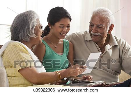 Granddaughter looking at a photo album with her grandparents View Large Photo Image Stock Photograph - Granddaughter looking at a photo album with her grandparents. Fotosearch