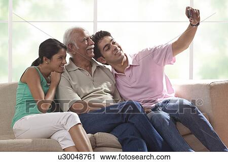 Stock Image - Grandfather and grandchildren taking a photograph of themselves. Fotosearch