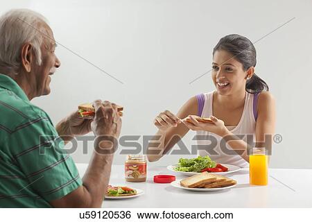 Stock Photograph - Grandfather and granddaughter eating breakfast. Fotosearch