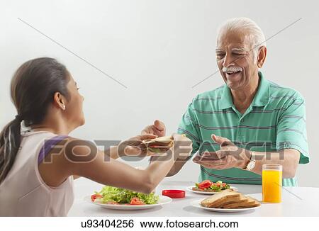 Stock Photograph - Grandfather and granddaughter eating breakfast. Fotosearch