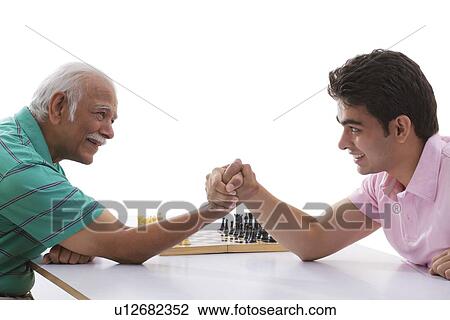 Stock Image - Grandfather and grandson doing arm wrestling. Fotosearch