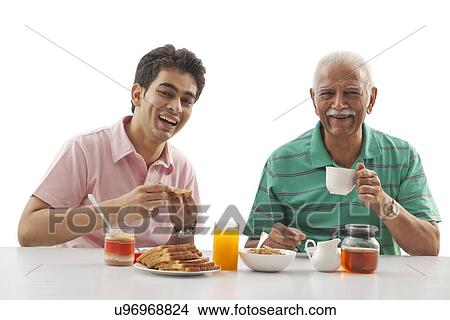 Picture - Grandfather and grandson eating breakfast. Fotosearch